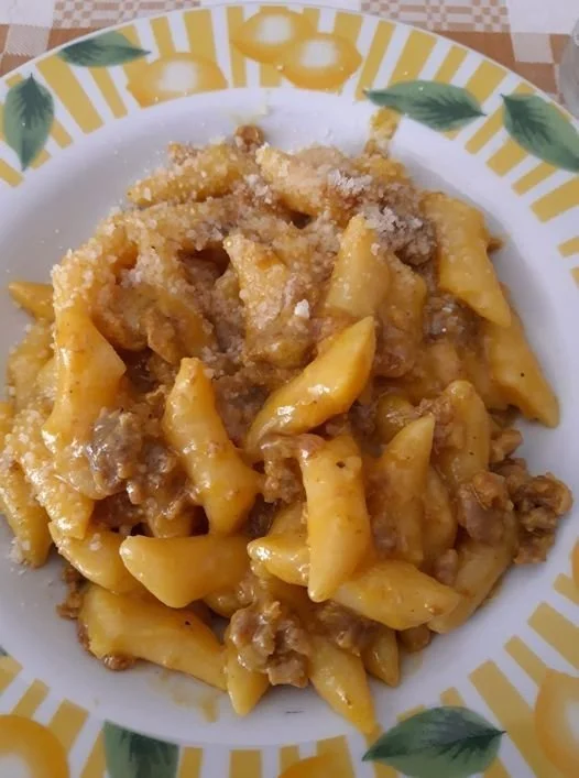 Gnocchi di patate con salsiccia, cipolla e zafferano in un piatto gustoso.